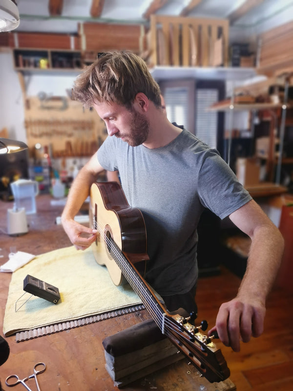 Man working on a guitar in a workshop setting