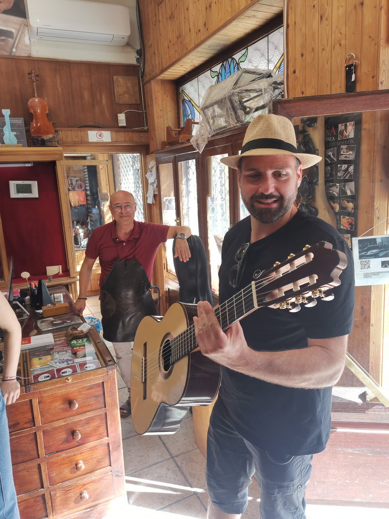 Man holding a guitar in a room with wooden furniture and stained glass window