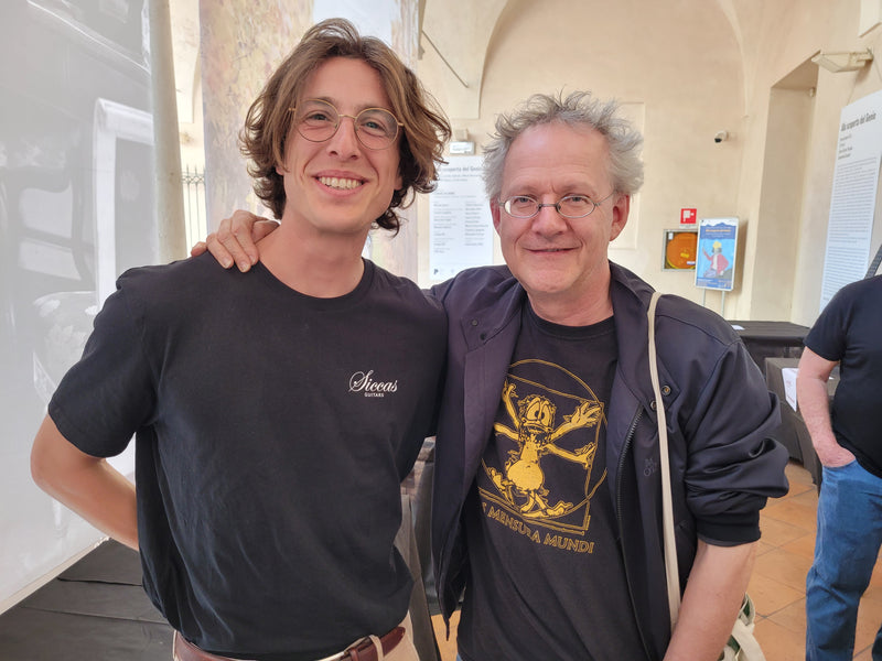 Two people standing upside down with a neutral background